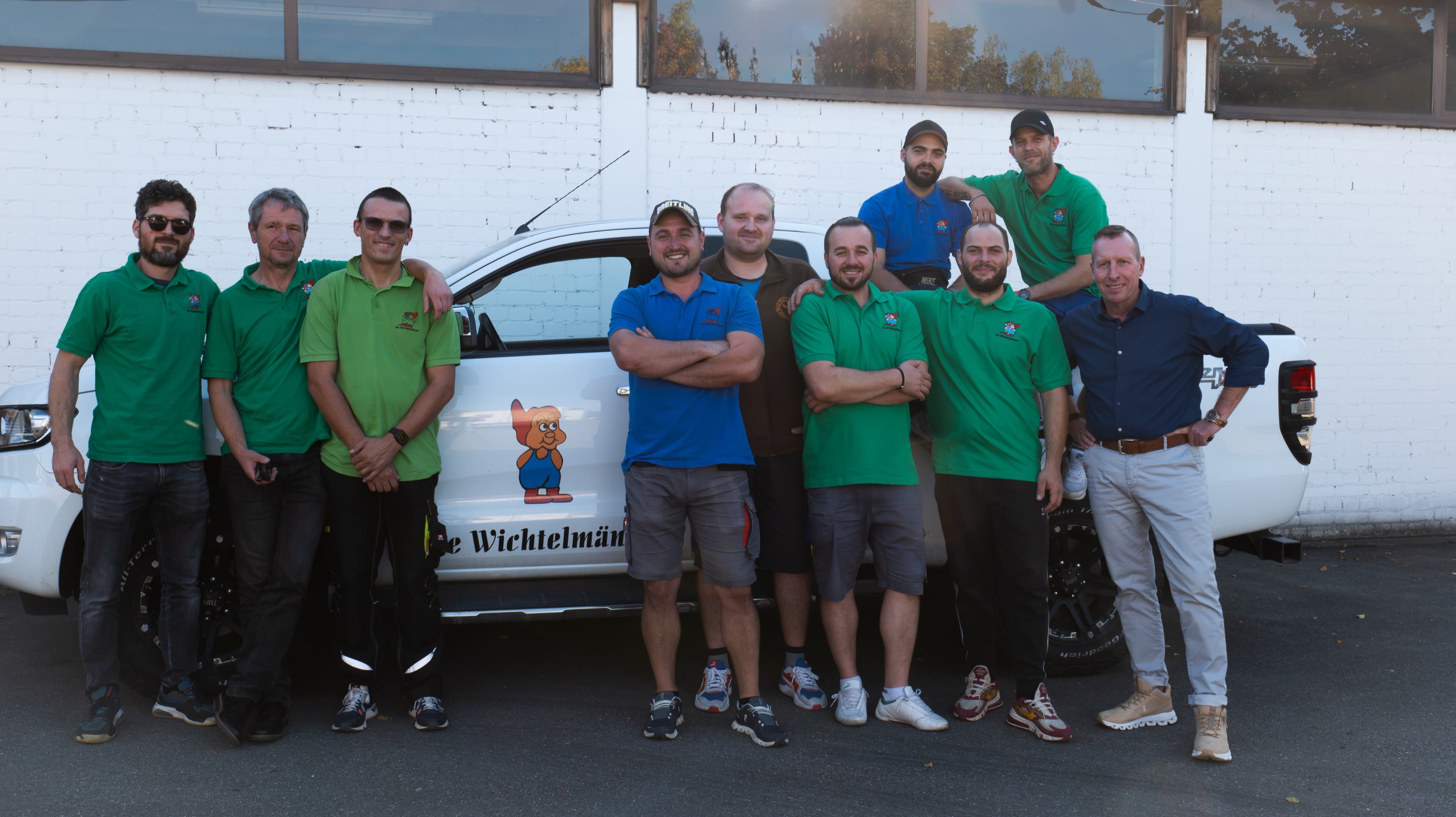Das Team der Wichtelmänner vor einem Firmenfahrzeug